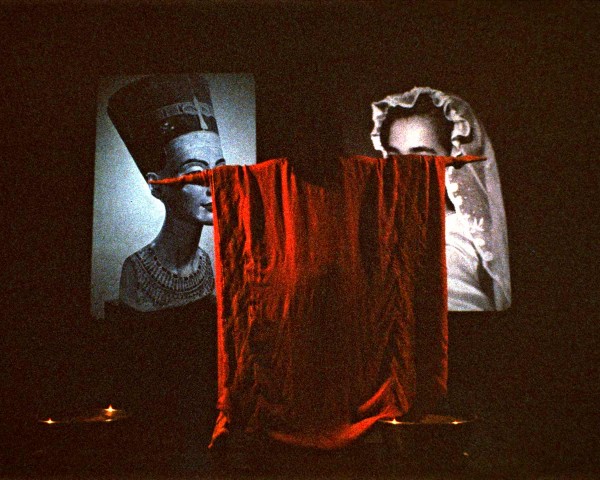 The voice on tape says: "Mount and straddle tubs of sand, which are now touching. . . face audience.", performance Nefertiti/Devonia Evangeline by Lorraine O’Grady.