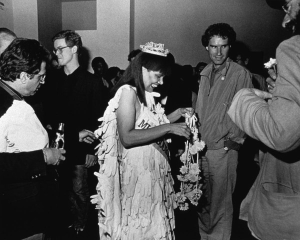 A skeptic inspects Mlle Bourgeoise Noire's cape. Mlle Bourgeoise Noire performance by Lorraine O'Grady.