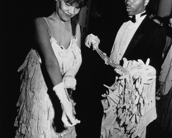 Mlle Bourgeoise Noire removes the cape and puts on her gloves. Mlle Bourgeoise Noire performance by Lorraine O'Grady.