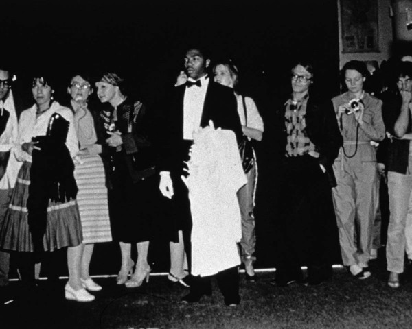 Crowd watches Mlle Bourgeoise Noire shouting her poem. Mlle Bourgeoise Noire performance by Lorraine O'Grady.